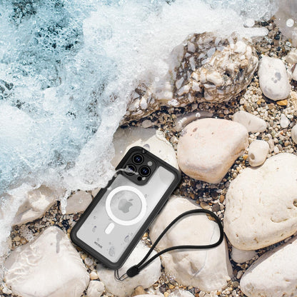 Motivecase Waterproof phone case for iPhone 15 Pro Max with attached wrist hand strap lanyard lying on beach rocks amidst ocean water splashes. **(23 words)**