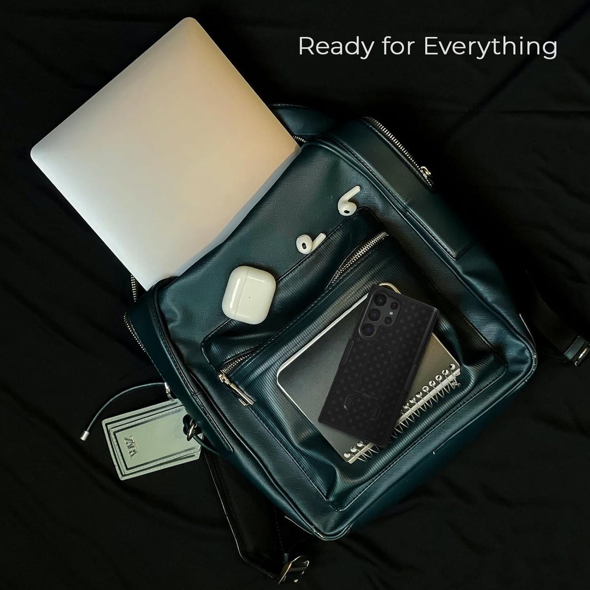 Top view flatlay of Motivecase Ranger V1 case for Samsung Galaxy S24 Ultra resting on dark green backpack with daily travel gear accessories.